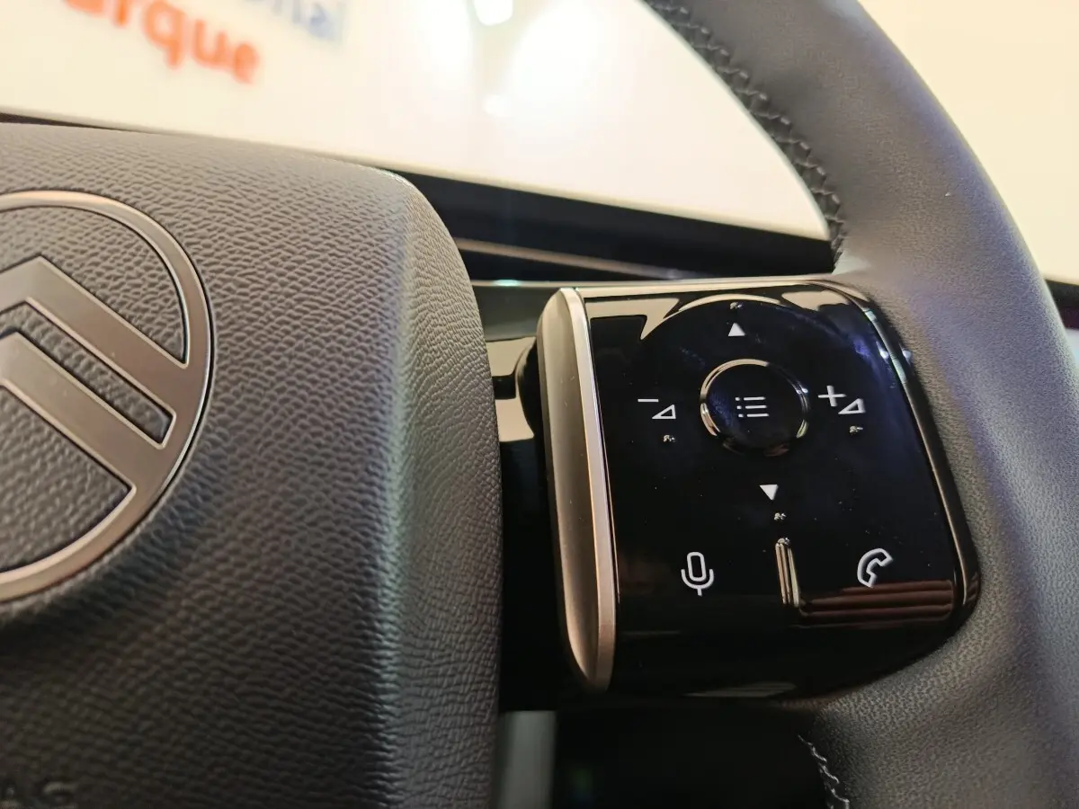 Gros plan sur les commandes tactiles noires du volant cuir de la Citroën C5 hybride gris foncé, intérieur moderne.