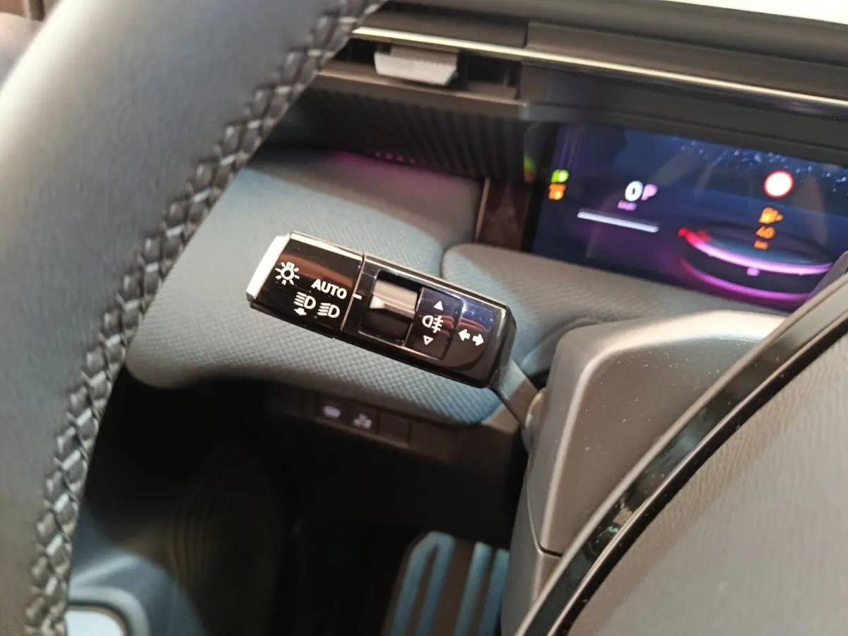 Gros plan sur la commande des feux à gauche du volant dans l’habitacle gris du Citroën C5 hybride 2026.