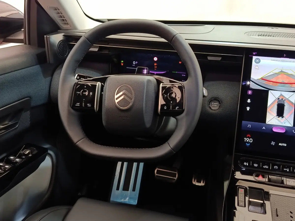Vue intérieure centrée sur le volant cuir noir de la Citroën C5 Hybride avec écran tactile et affichage multifonctions.