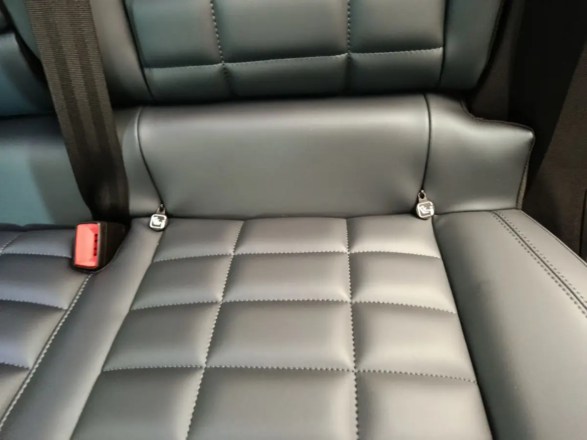 Gros plan sur la banquette arrière en cuir gris foncé de la Citroën C5 Hybride 2026 avec ceintures et ancrages Isofix visibles.