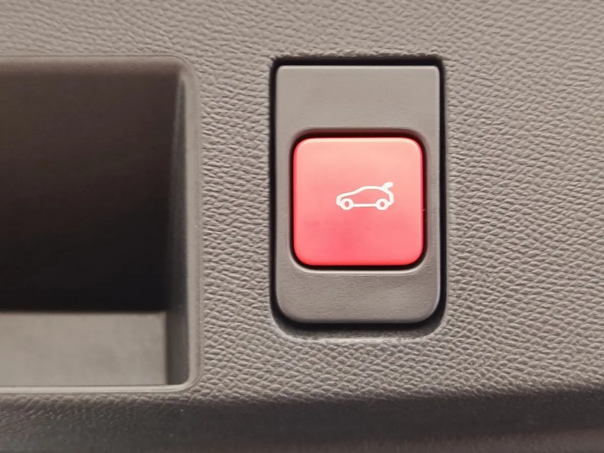 Bouton rouge d'ouverture électrique du coffre sur tableau de bord intérieur d'une Citroën C5 Hybride gris foncé.