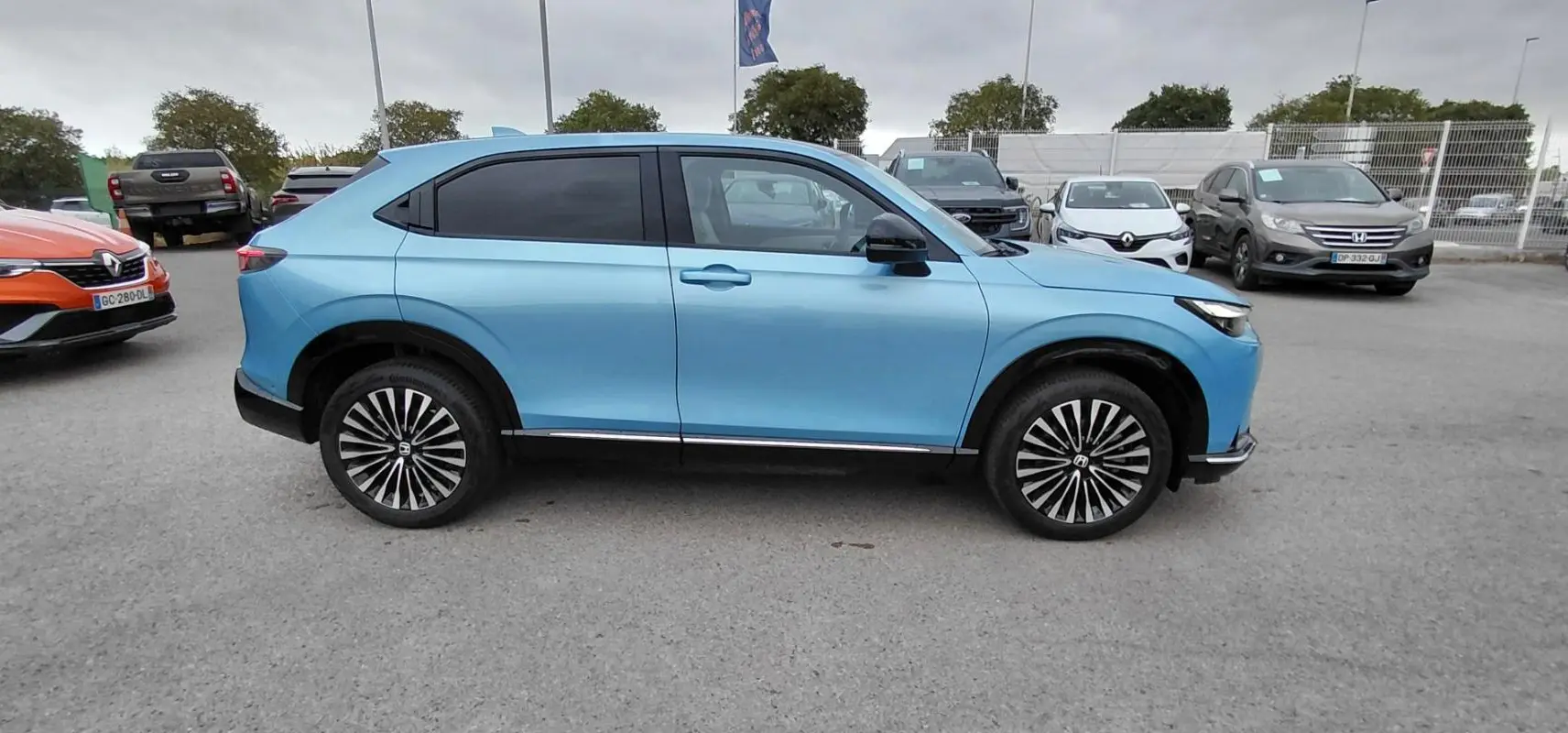 Vue de profil côté gauche du SUV électrique Honda e:Ny1 204 ch Advance bleu 2025 avec jantes distinctives bicolores.