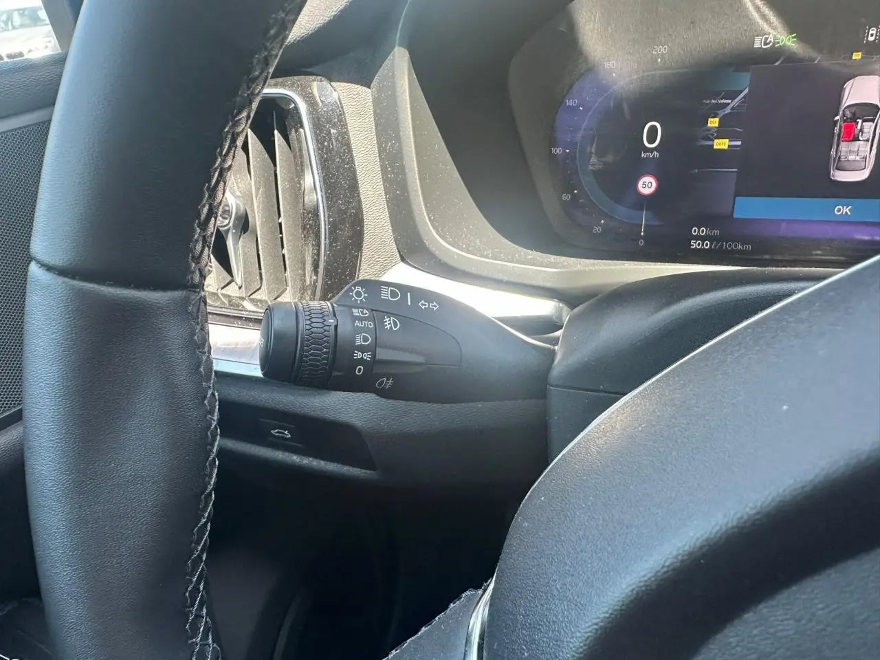 Vue intérieure côté gauche du volant noir d'une Volvo S60 2024 avec tableau de bord digital et commandes lumineuses intégrées.