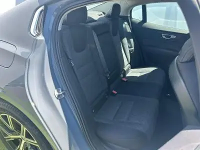 Vue intérieure arrière gauche du Volvo S60 2024 Thunder Grey Metal montrant la banquette arrière en tissu noir