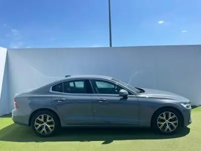 Profil latéral droit d'une Volvo S60 2024 en Thunder Grey Metal avec jantes alliage 17 pouces sur fond clair extérieur.