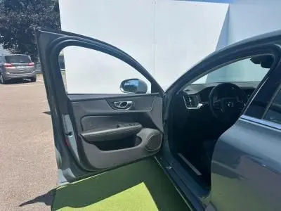 Portière avant gauche ouverte d'une Volvo S60 Thunder Grey Metal 2024, intérieur noir visible côté conducteur.