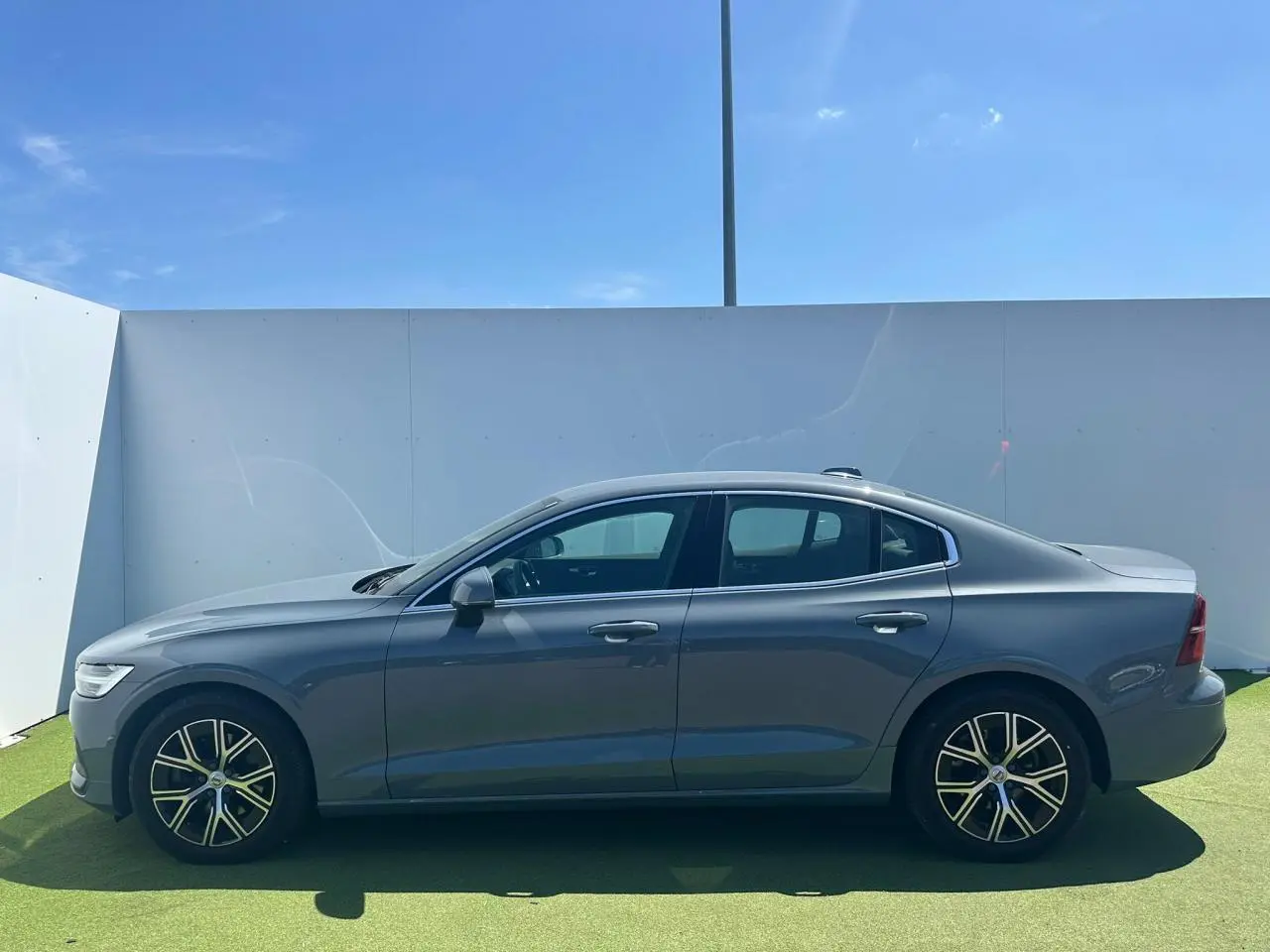 Profil latéral droit d'une Volvo S60 2024 Thunder Grey Metal avec jantes alliage 17 pouces en Y noir et diamant.