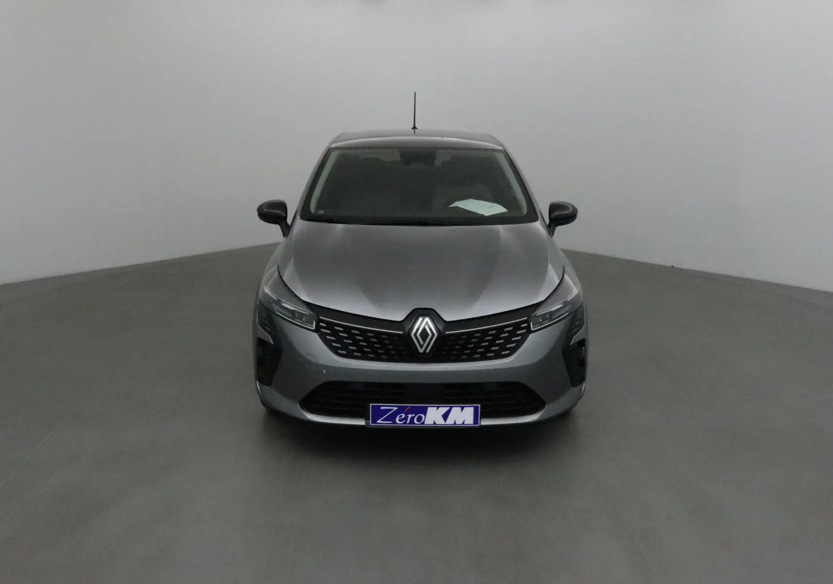 Vue frontale d'une Renault Clio V gris schiste avec calandre noire et logo Renault bien visible.
