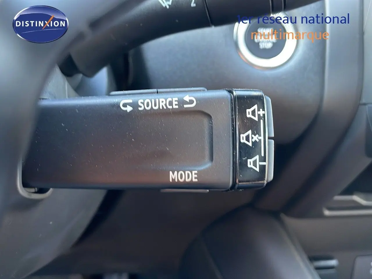 Gros plan sur la commande au volant du Renault Captur blanc nacré, avec boutons source et mode visibles.