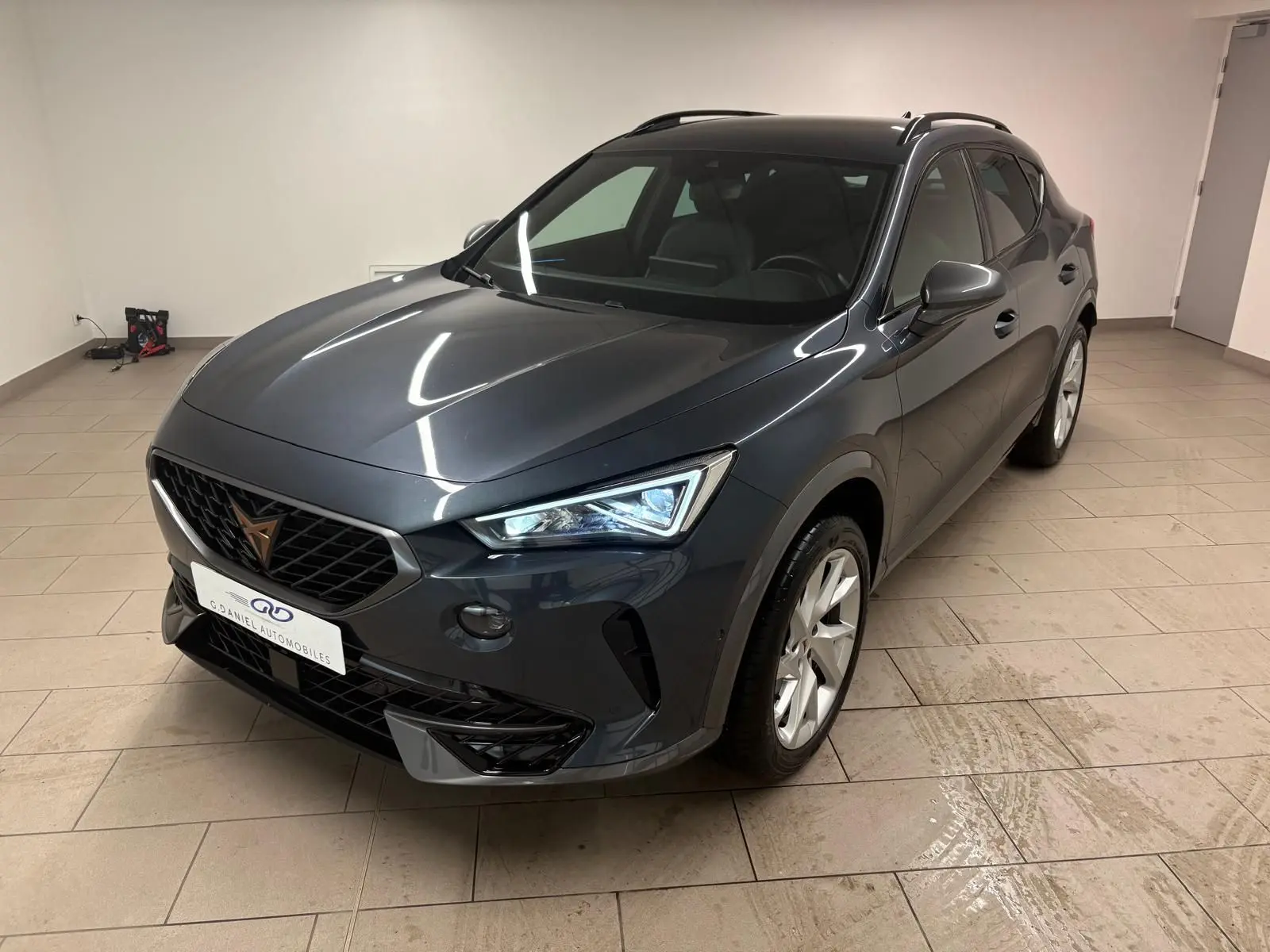 Vue 3/4 avant droit du CUPRA Formentor gris magnétique 2024, avec calandre noire et jantes argentées en intérieur.