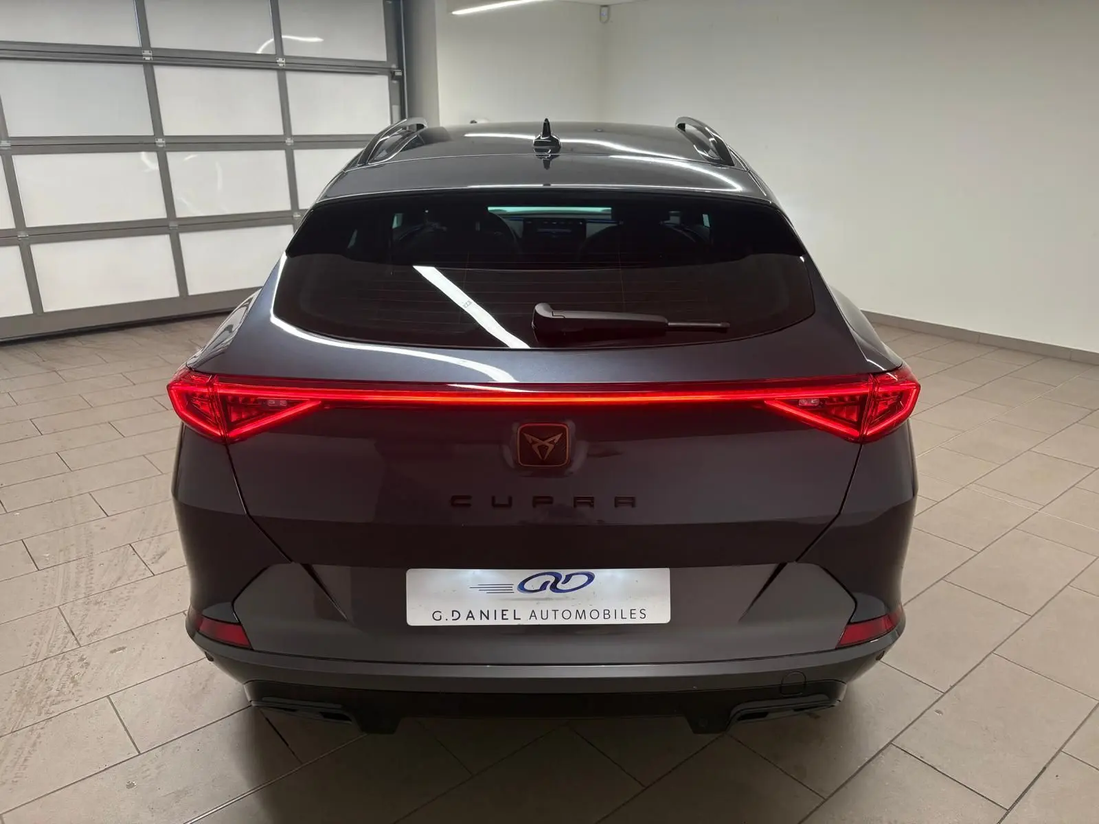Vue arrière du CUPRA Formentor 1.5 TSI gris magnétique avec feux LED allumés dans un garage.