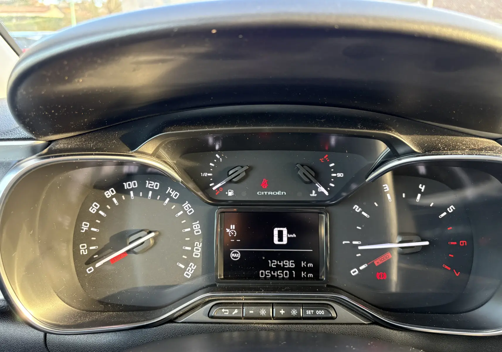 Vue rapprochée du tableau de bord de la Citroën C3 rouge, affichant les compteurs et l'écran digital central.