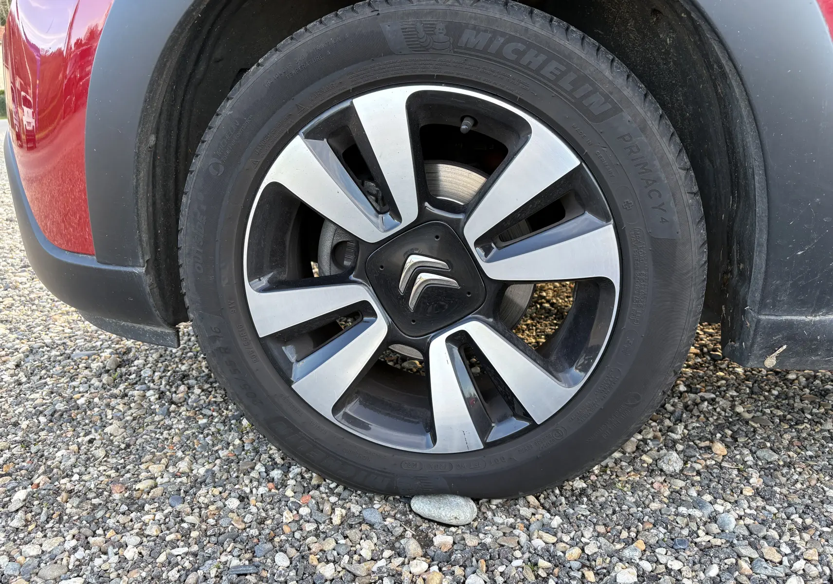 Gros plan sur la roue avant gauche rouge d'une Citroën C3 1.2 PureTech avec jante alliage bicolore et logo Citroën central.