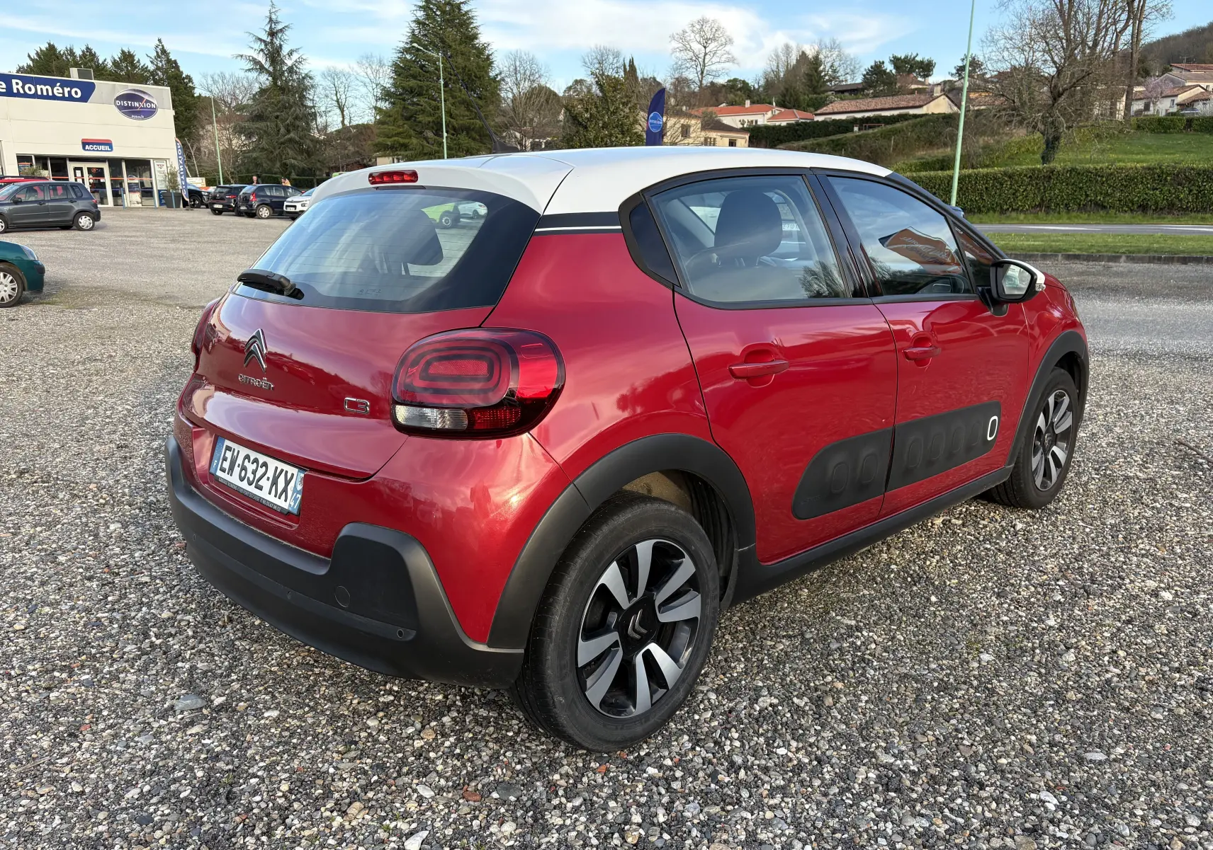 Vue 3/4 arrière droite d'une Citroën C3 rouge avec toit blanc et protections Airbump noires sur le côté droit.