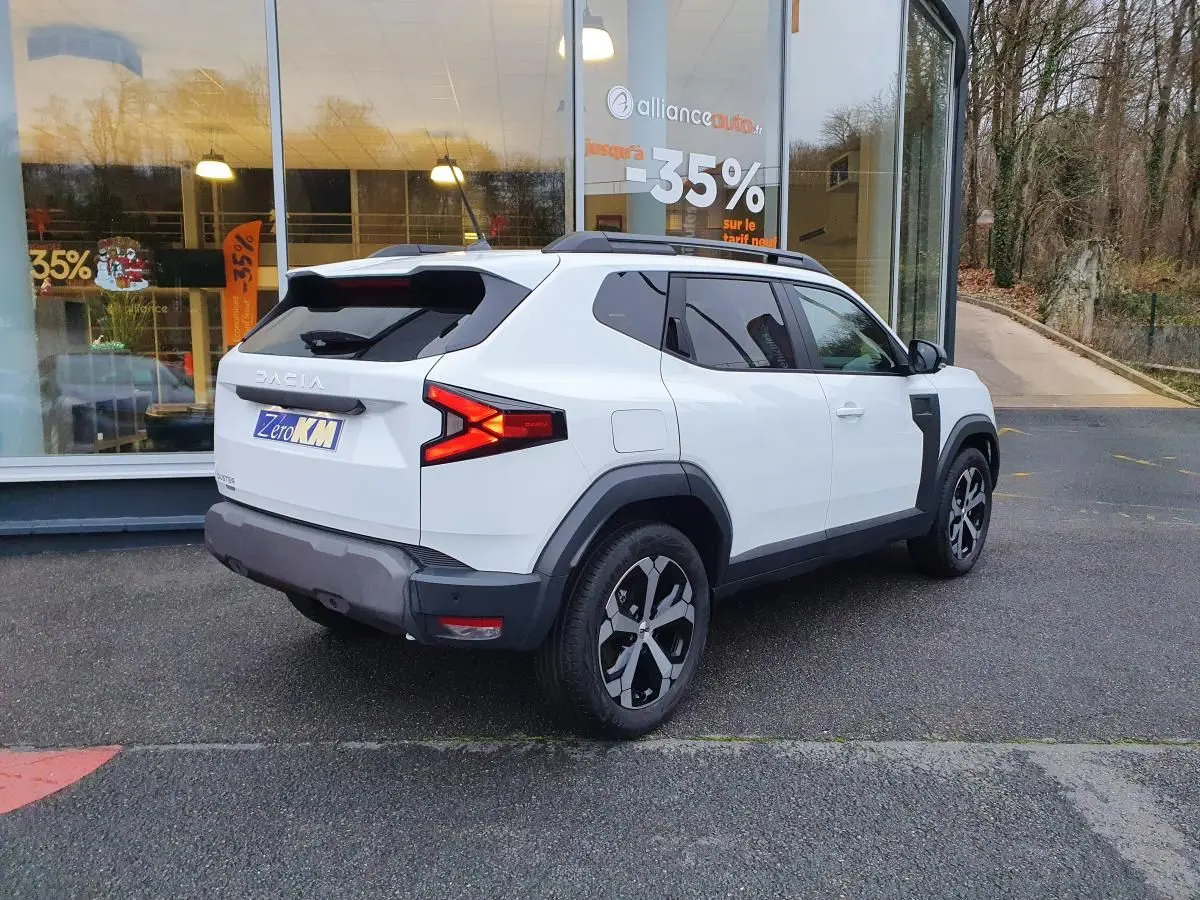 Vue 3/4 arrière droit du Dacia Duster 1.6 Hybrid 140 blanc glacier avec jantes alliage 18" diamantées.
