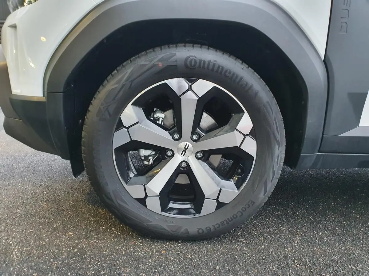 Gros plan sur la roue avant droite du Dacia Duster blanc glacier, jante alliage 18” diamantée Tagasan.