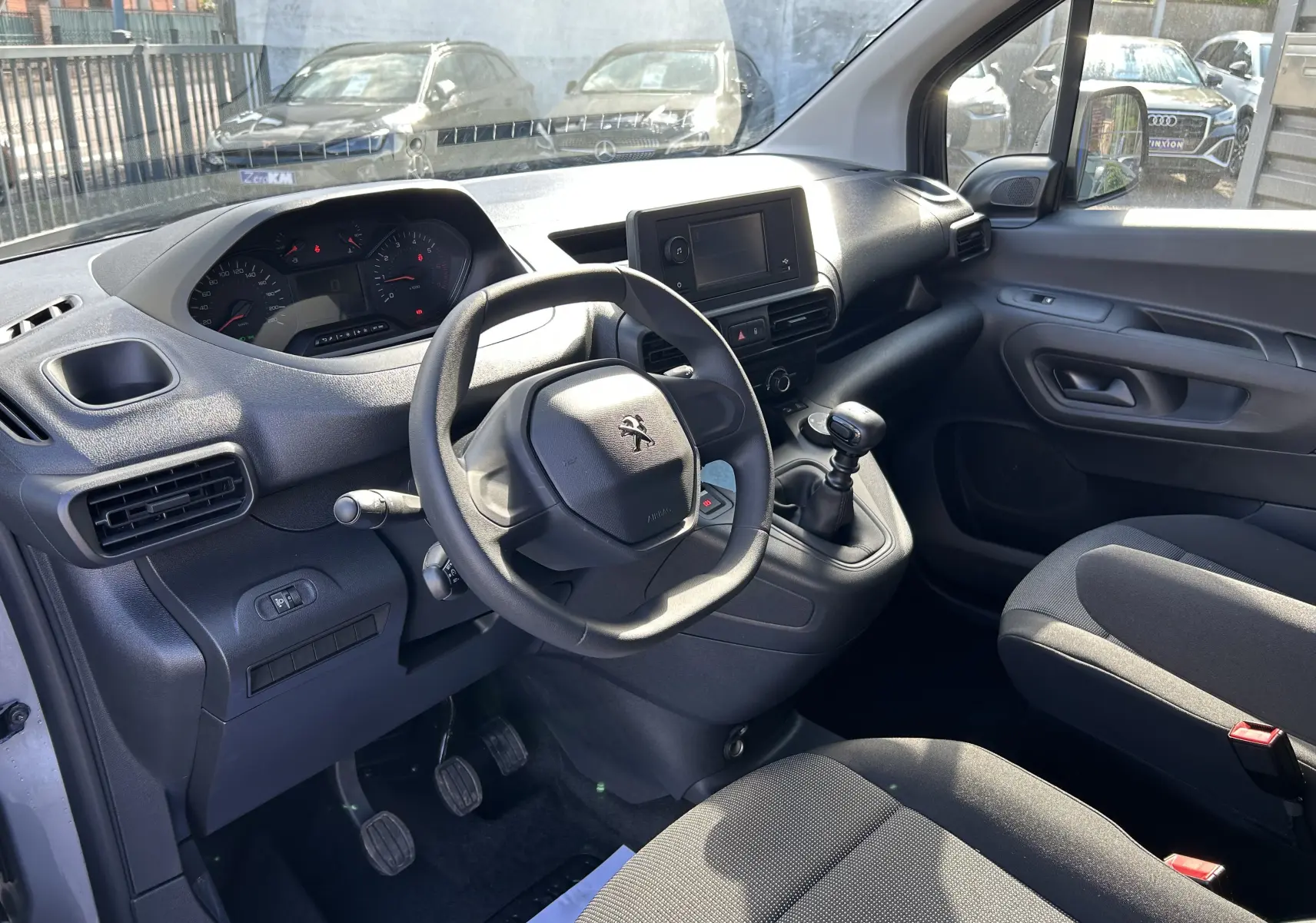 Vue intérieure côté conducteur du Peugeot Partner Dangel 4x4 gris Artense, montrant le volant, tableau de bord et levier de vitesse manuel.