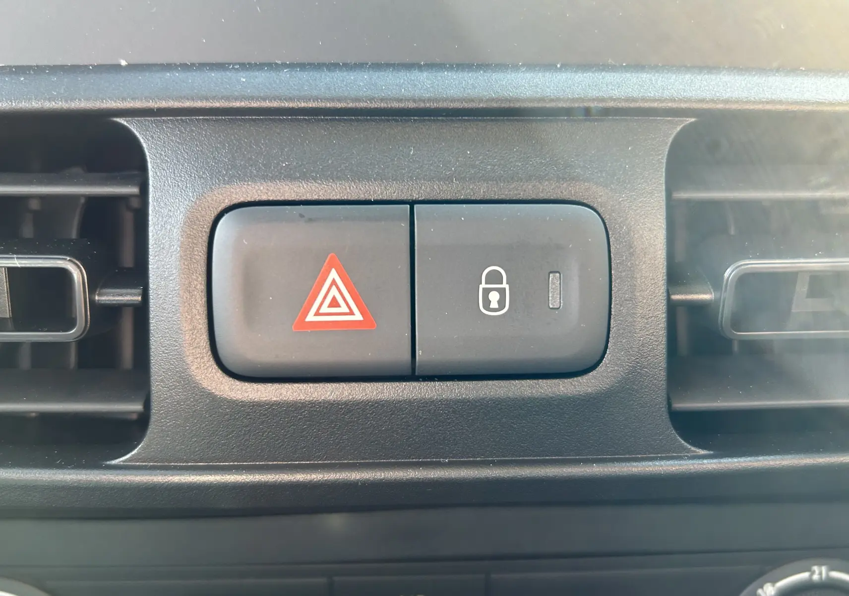 Gros plan sur les boutons de warning et verrouillage central du tableau de bord du Peugeot Partner Dangel gris Artense.
