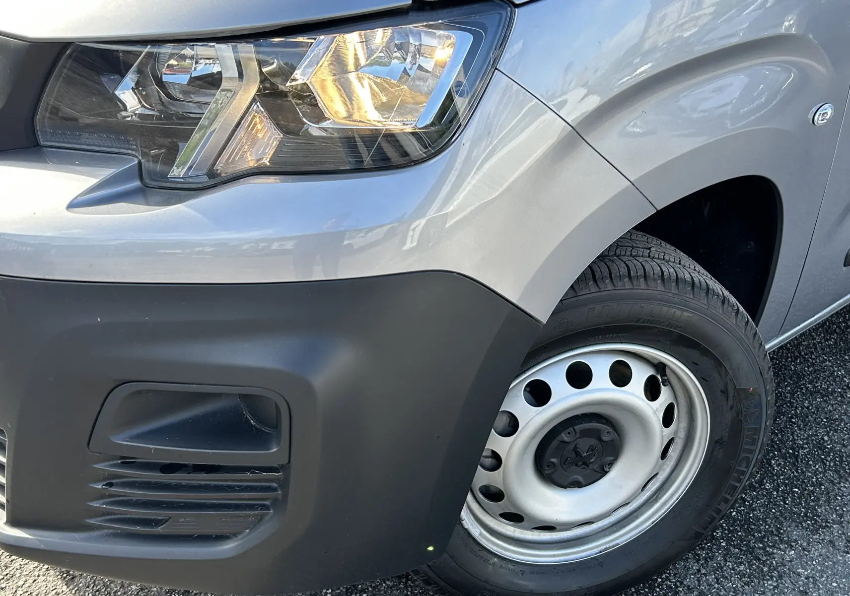 Gros plan sur l’avant droit gris Artense du DANGEL Partner 4x4, mettant en valeur le phare et la roue acier.