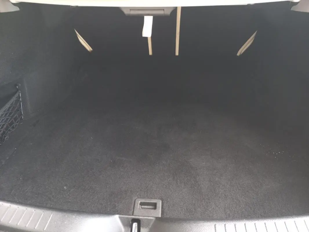 Coffre vide en vue plongeante d'une Mercedes Classe C Coupé blanc, intérieur noir avec filet de rangement latéral.