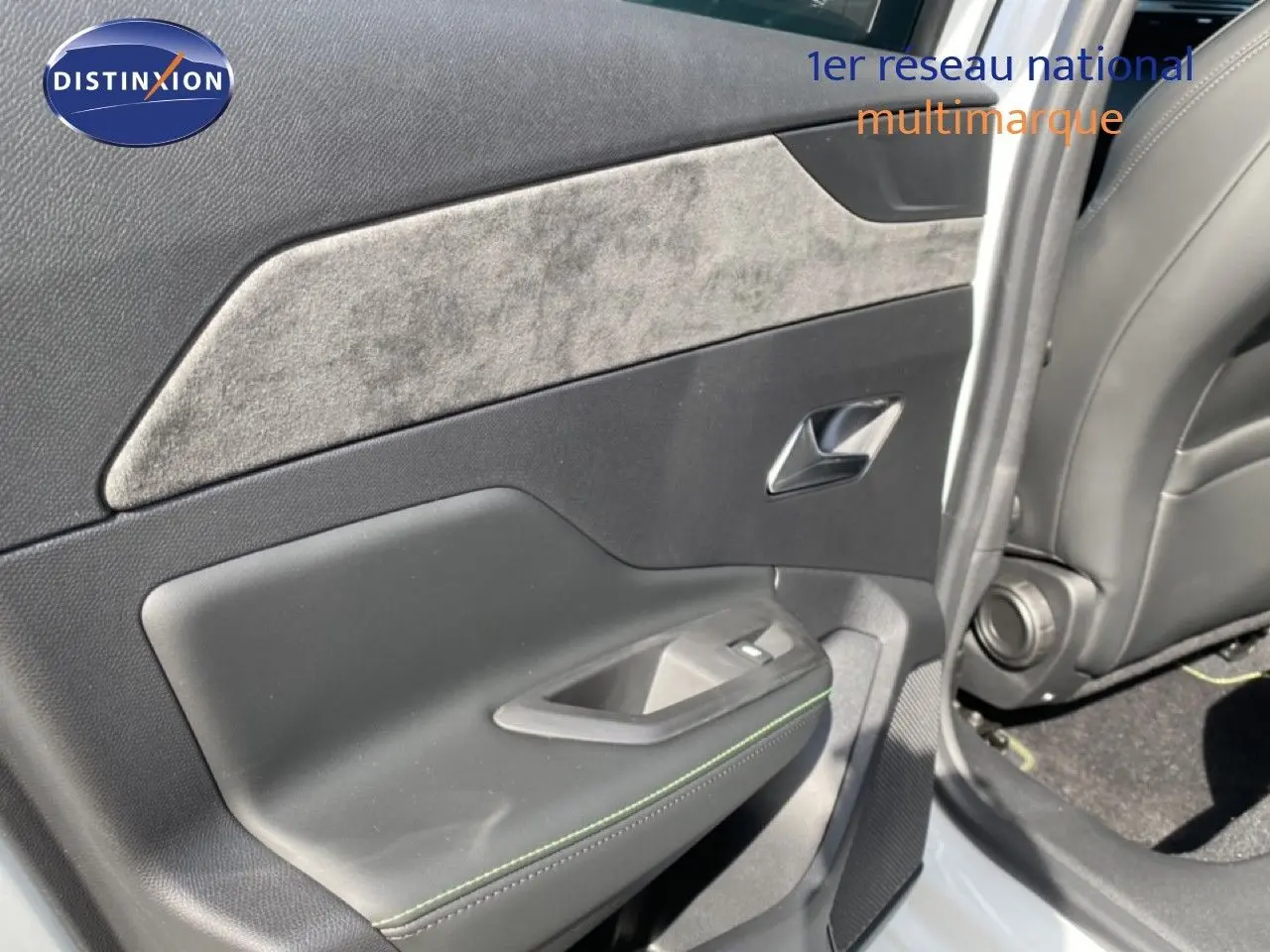Vue rapprochée de la porte arrière gauche d'une Peugeot 308 Hybrid blanche, avec garniture tissu gris et coutures vertes.
