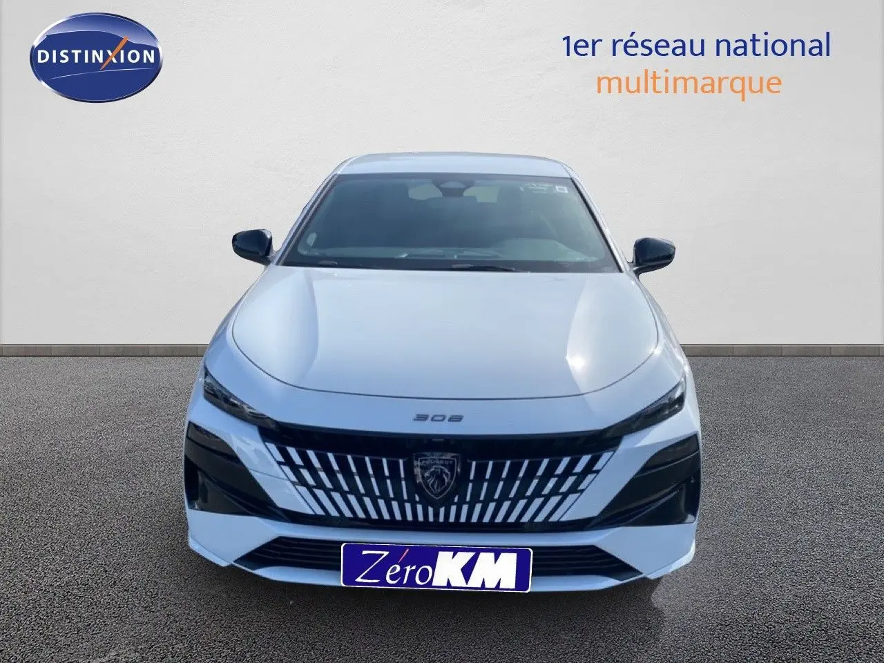 Vue frontale d'une Peugeot 308 Hybrid 145ch GT blanche Okenite Metal avec calandre noire distinctive et logo lion central.