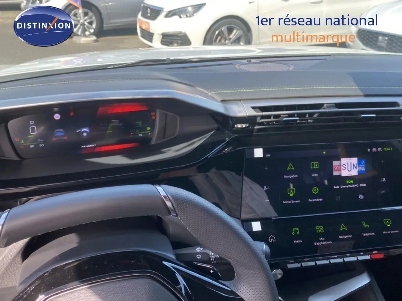 Vue intérieure du tableau de bord et volant de la Peugeot 308 Hybrid 145ch GT blanche, avec écran numérique et interface tactile.
