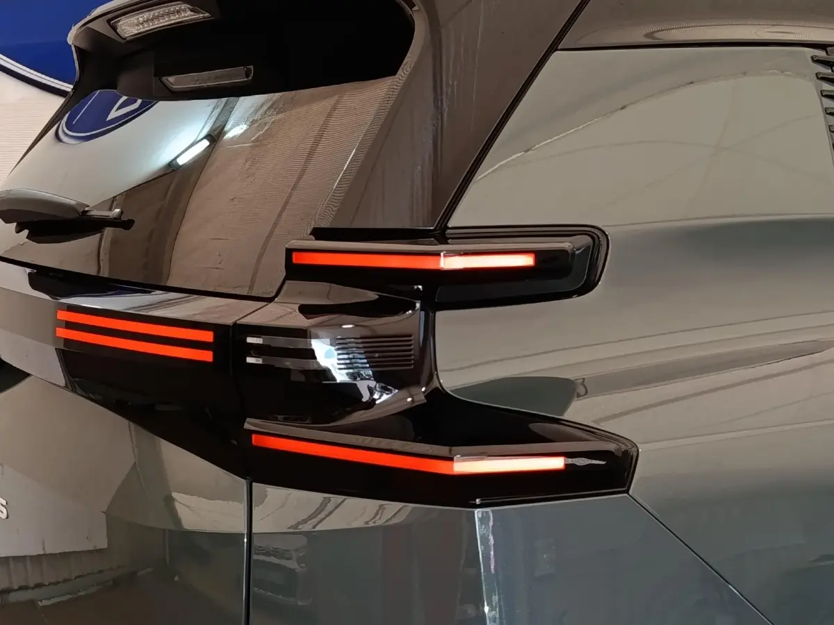 Gros plan sur le feu arrière droit allumé d'une Citroën C5 hybride verte, soulignant ses lignes modernes et brillantes.