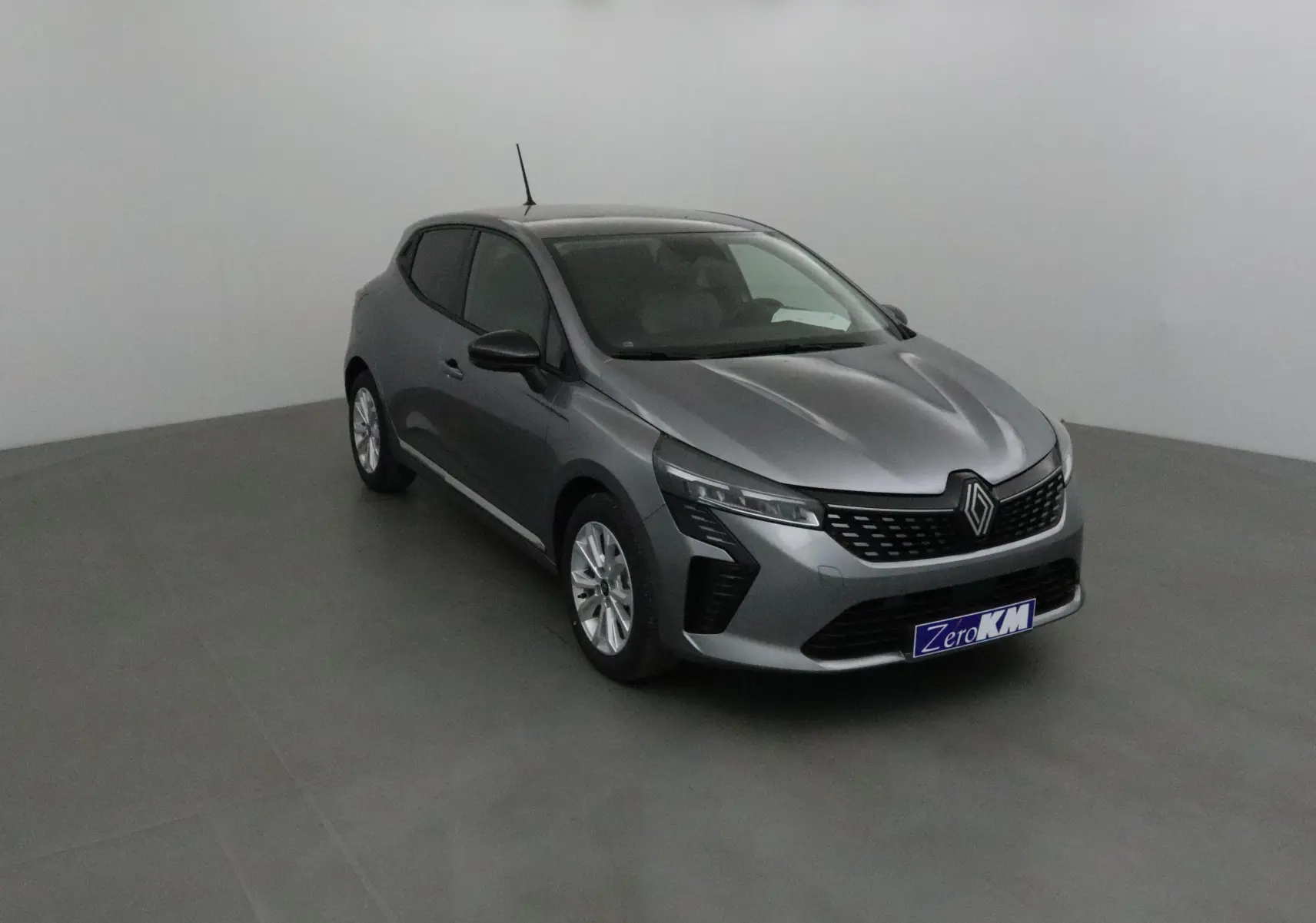 Renault Clio V gris schiste vue 3/4 avant droit avec protections latérales chromées dans un studio neutre.