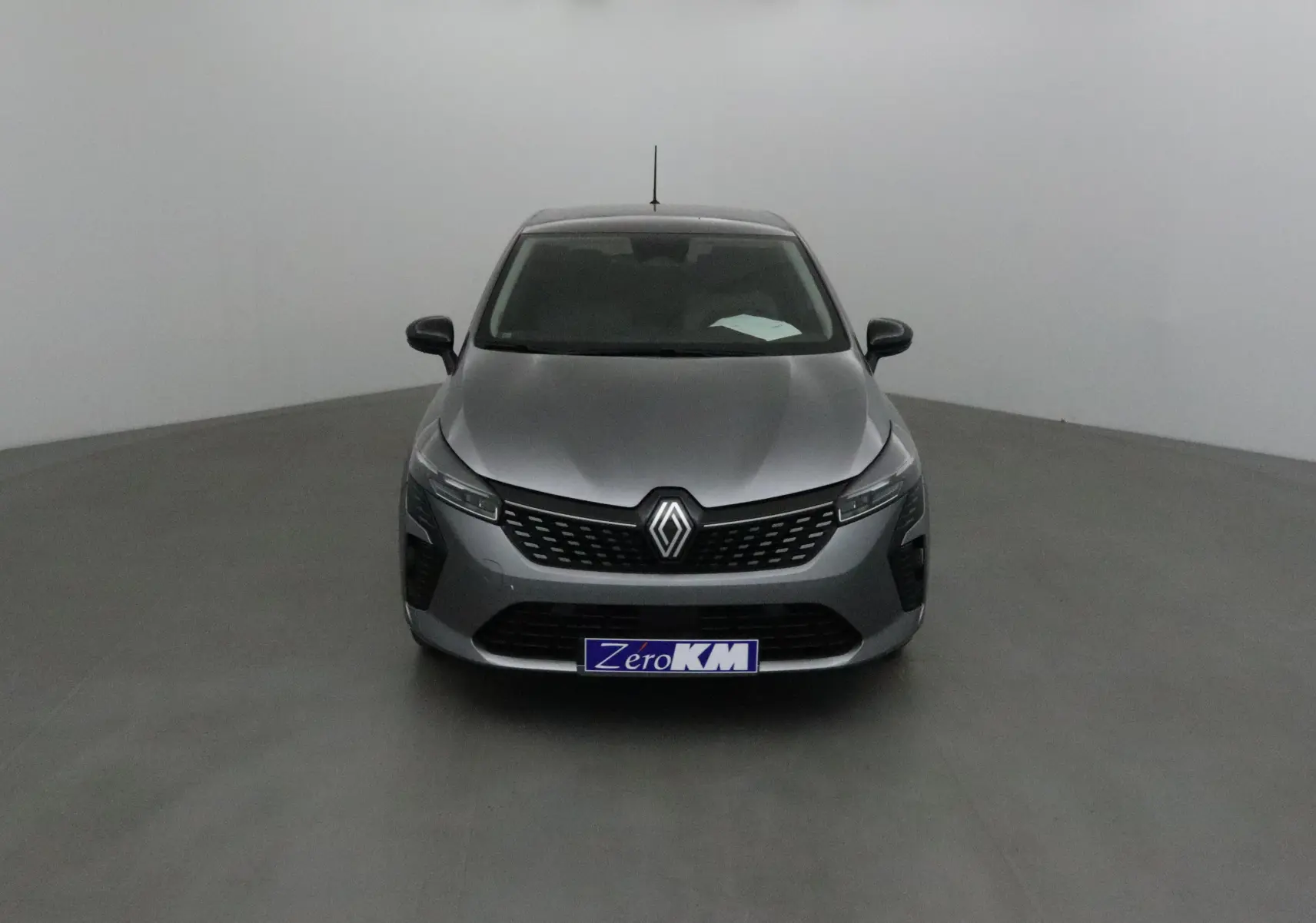 Renault Clio V gris schiste vue de face dans un studio, avec calandre moderne et phares fins LED.