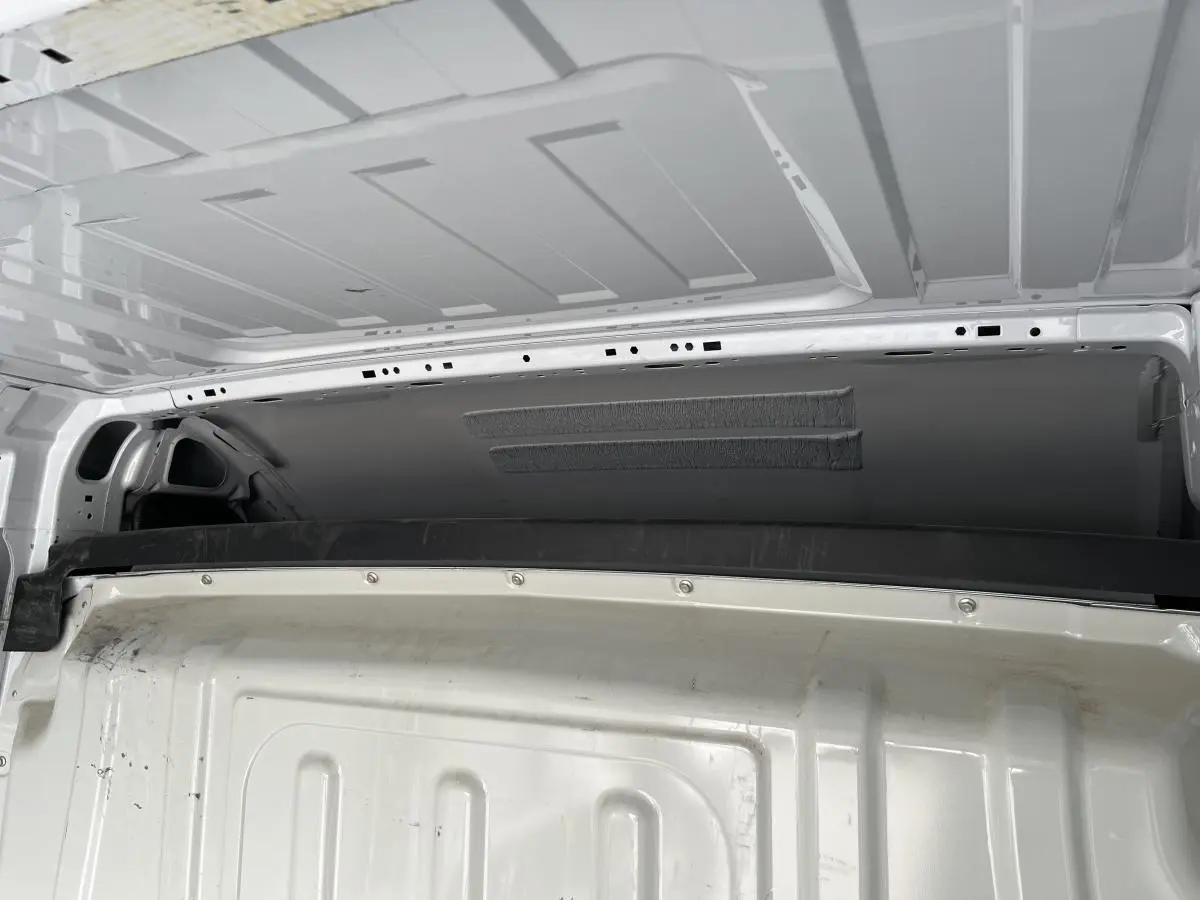 Vue intérieure du fourgon Peugeot Boxer blanc montrant la cloison tôlée séparant l'habitacle et la zone de chargement.