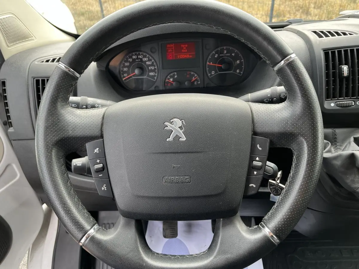 Volant en cuir noir avec logo Peugeot, tableau de bord et compteur digital du Boxer Fourgon 2023 vus de face.