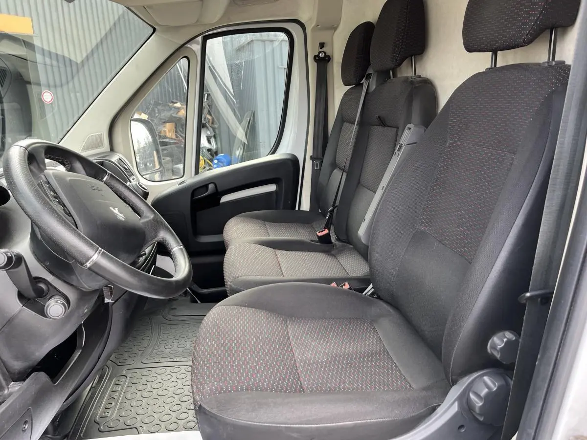 Vue intérieure côté conducteur du Peugeot Boxer Fourgon 2023, sièges tissu gris foncé avec motifs rouges.
