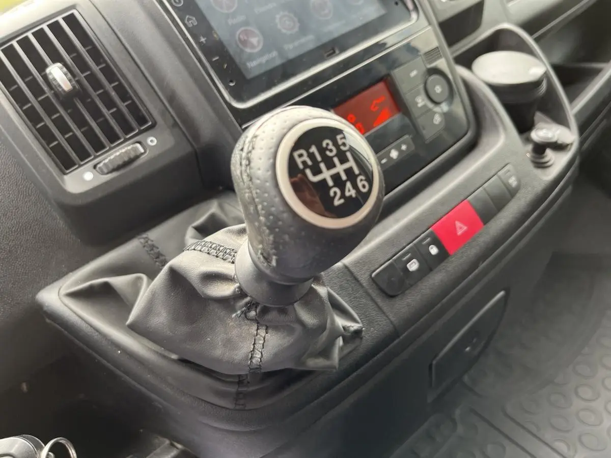 Gros plan sur le levier de vitesses manuel noir du Peugeot Boxer Fourgon 2023 avec tableau de bord et commandes visibles.