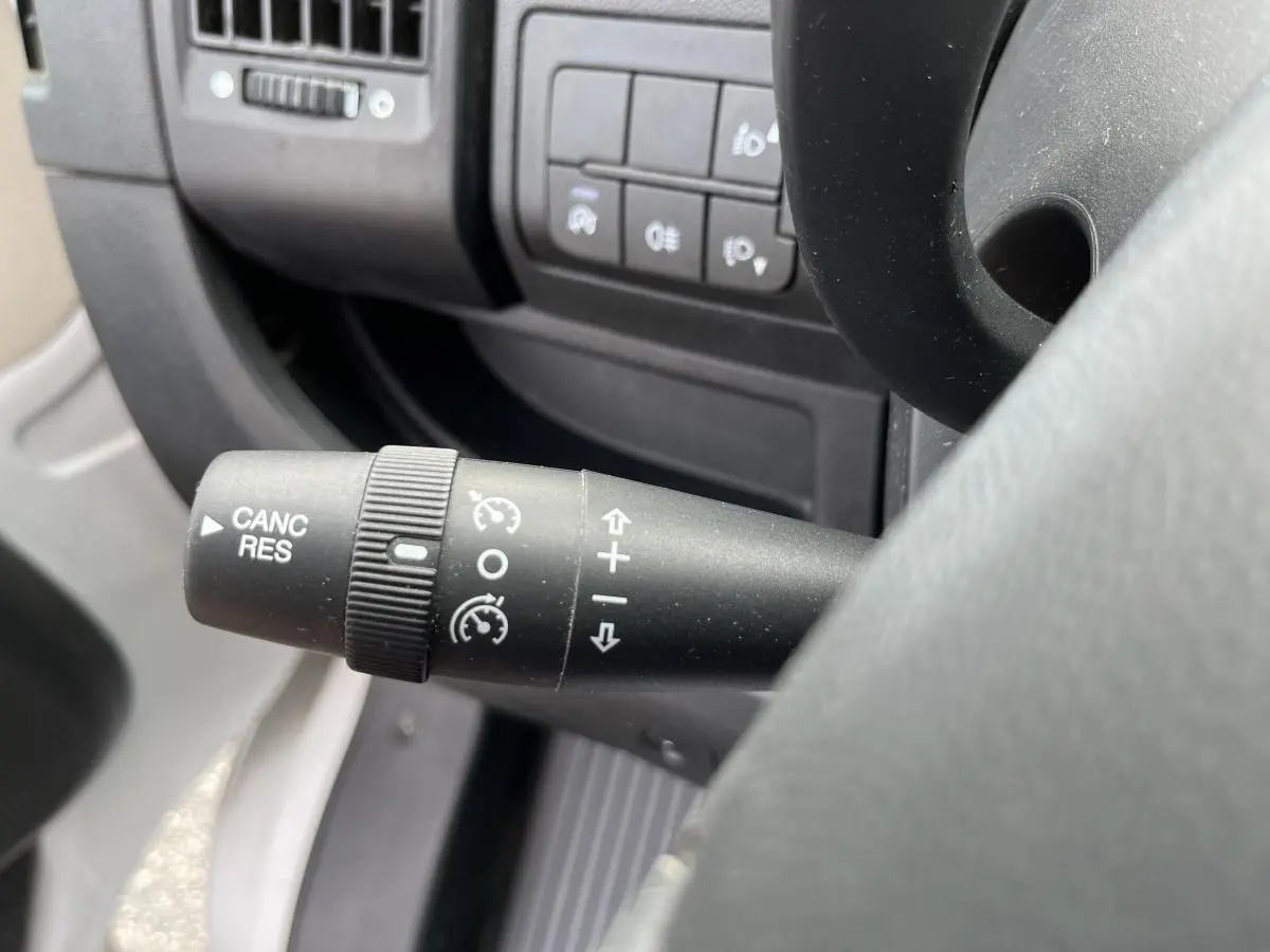 Gros plan sur la commande de régulateur de vitesse à gauche du volant du Peugeot Boxer Fourgon blanc 2023.