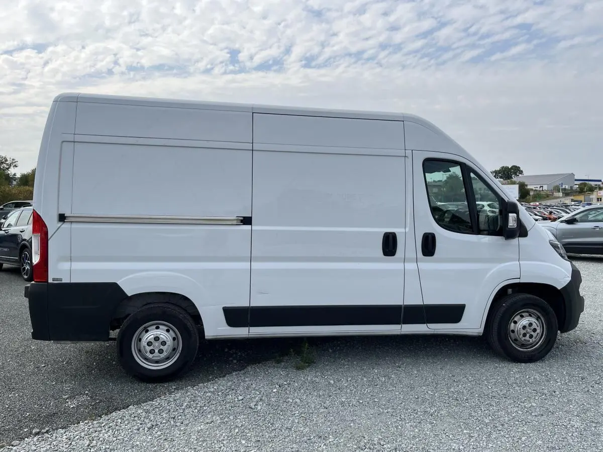 Profil droit d’un utilitaire blanc Peugeot Boxer Fourgon 2023 avec porte latérale coulissante tôlée et jantes acier.