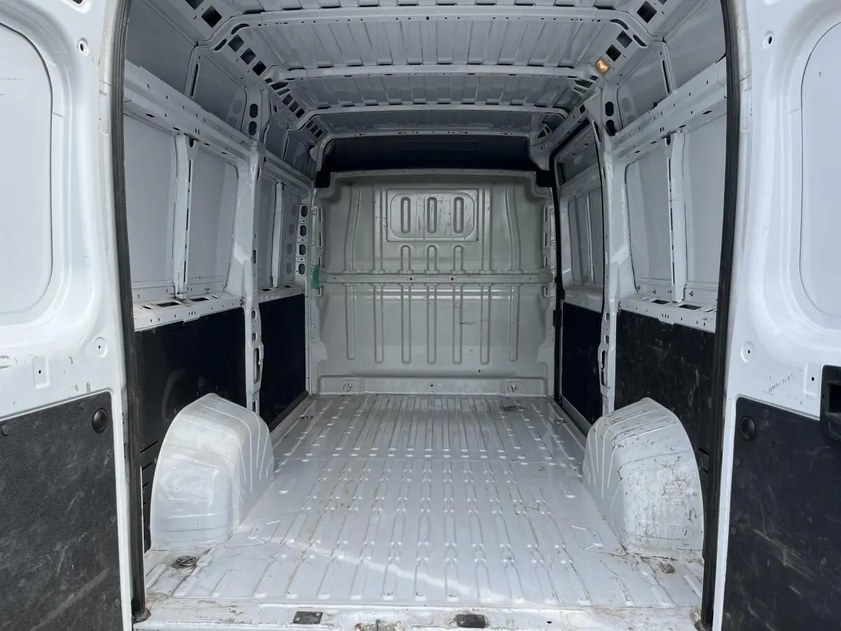 Intérieur vide du fourgon Peugeot Boxer blanc, vue de l'arrière vers l'avant avec cloison tôlée et panneaux latéraux noirs.
