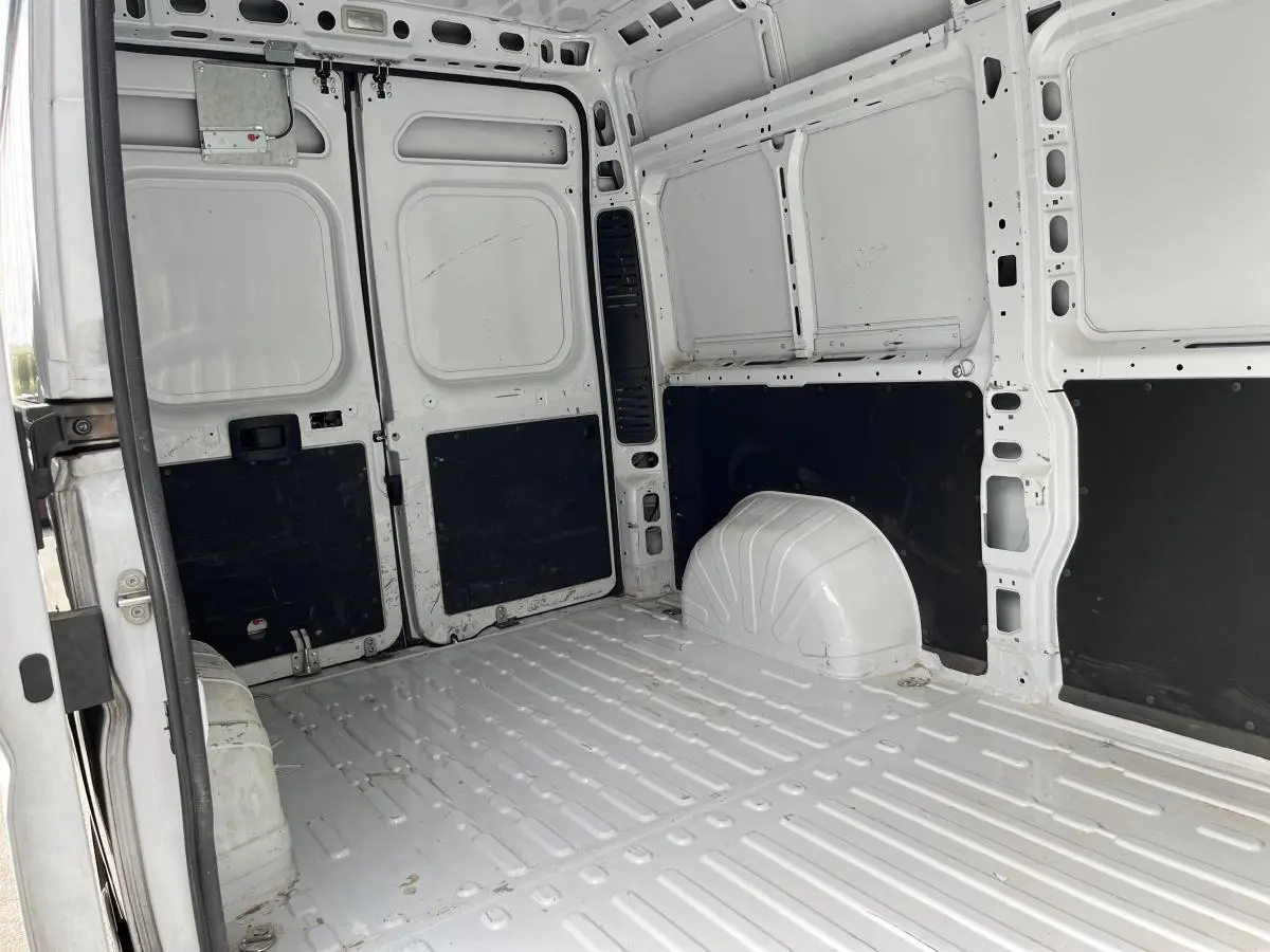 Intérieur du coffre blanc du Peugeot Boxer Fourgon 2023, vue arrière avec panneaux latéraux noirs et sol métallique.