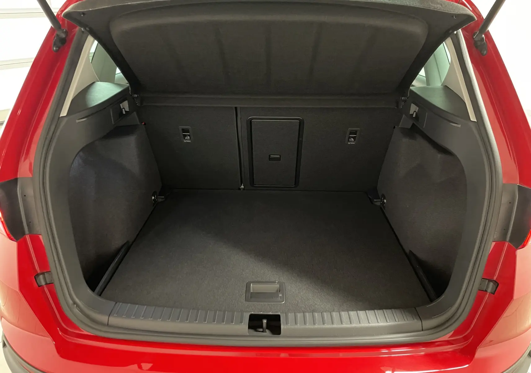 Coffre ouvert vu de l'arrière d'un SEAT Ateca 2024 Rouge Velvet, montrant un espace de chargement propre et spacieux.