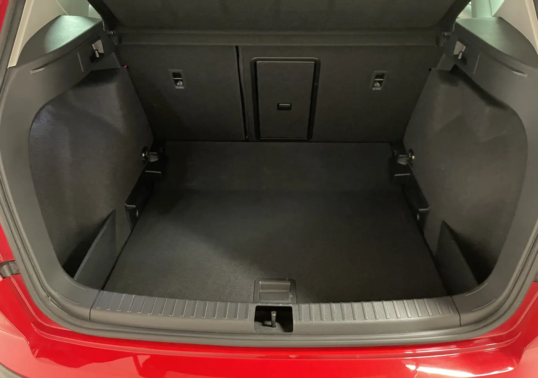 Coffre ouvert d'un SEAT Ateca 2024 Rouge Velvet, vue arrière montrant l'espace de chargement vide et les finitions intérieures noires.