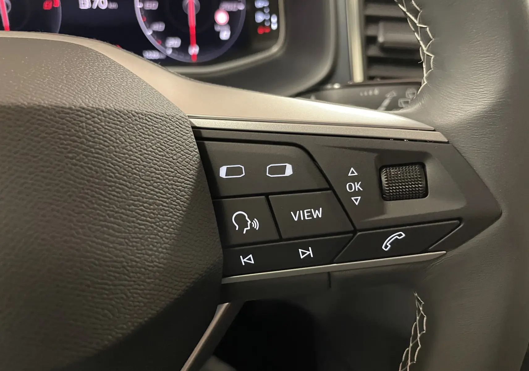 Gros plan sur les commandes du volant du SEAT Ateca 2024, finition Copa, avec cuir noir et coutures apparentes.