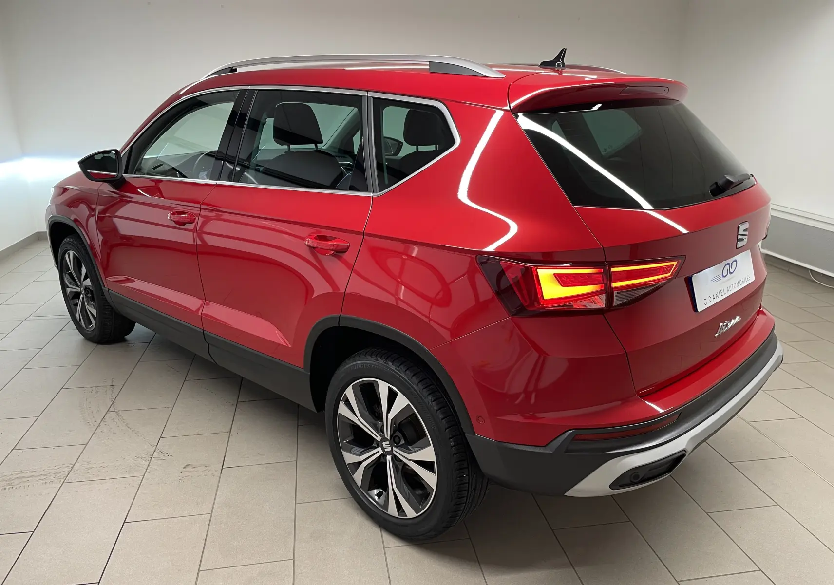 Vue 3/4 arrière droite du SEAT Ateca Rouge Velvet avec jantes 18 pouces usinées et feux arrière allumés.