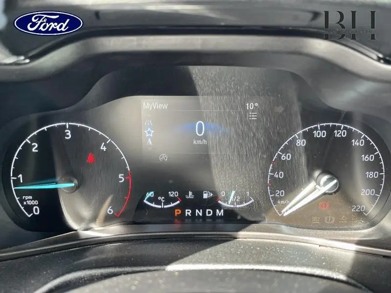 Vue rapprochée du tableau de bord numérique du Ford Transit Connect blanc glacier, affichant vitesse et indicateurs.