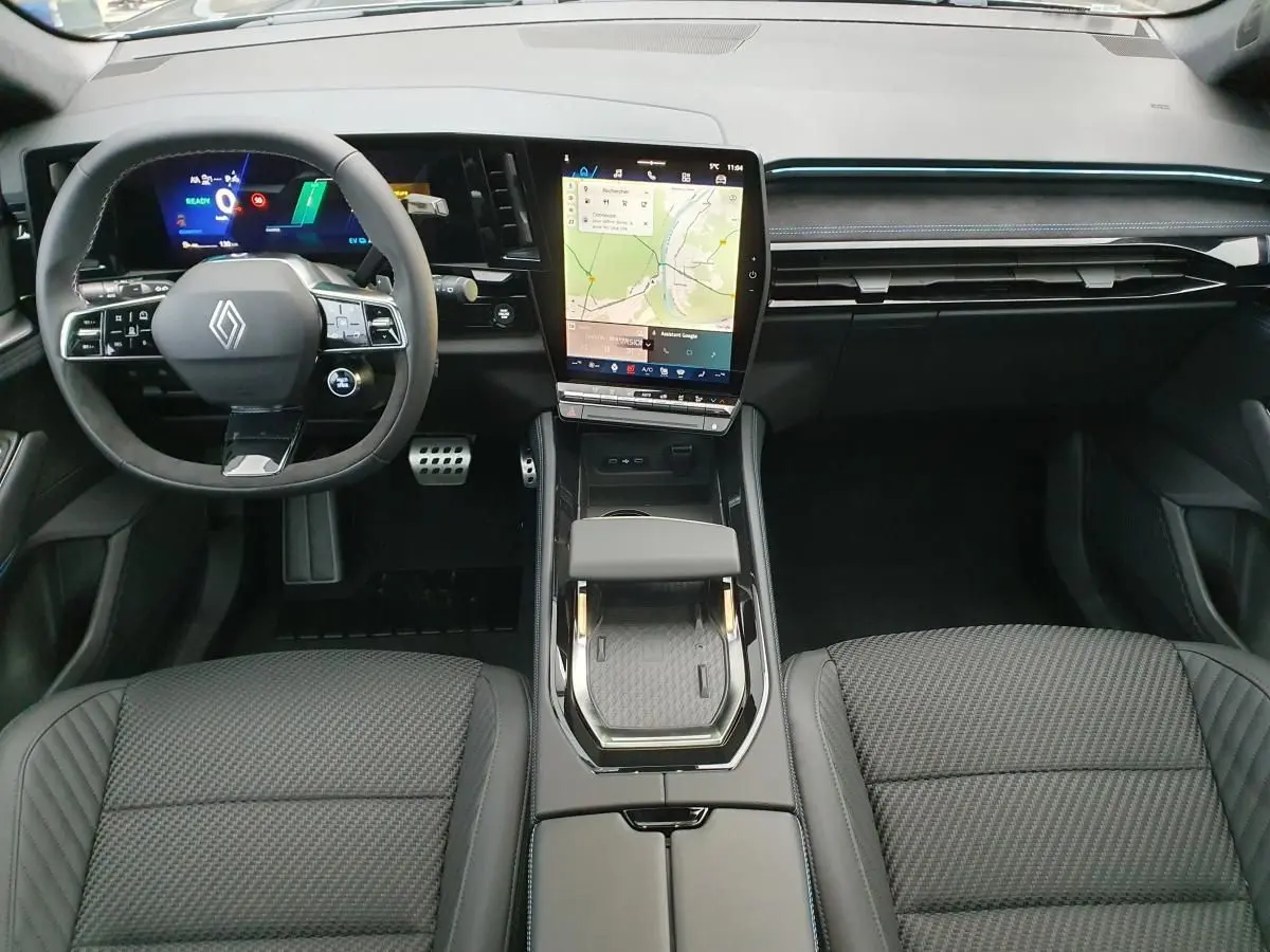 Vue intérieure avant du Renault Austral 2025, tableau de bord moderne avec écran tactile vertical et volant Alcantara noir.