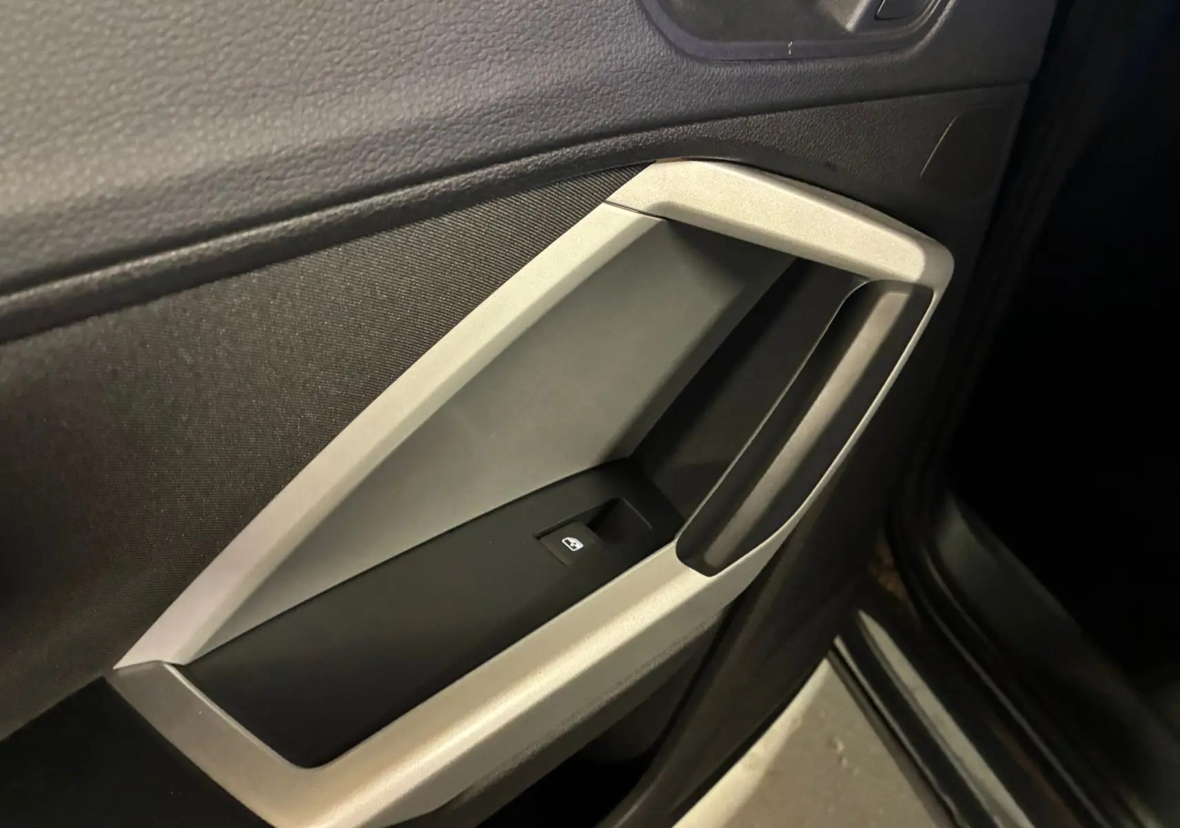 Gros plan sur la poignée intérieure côté gauche de la porte d’un Audi Q3 Sportback gris avec encadrement argent micrométallique.