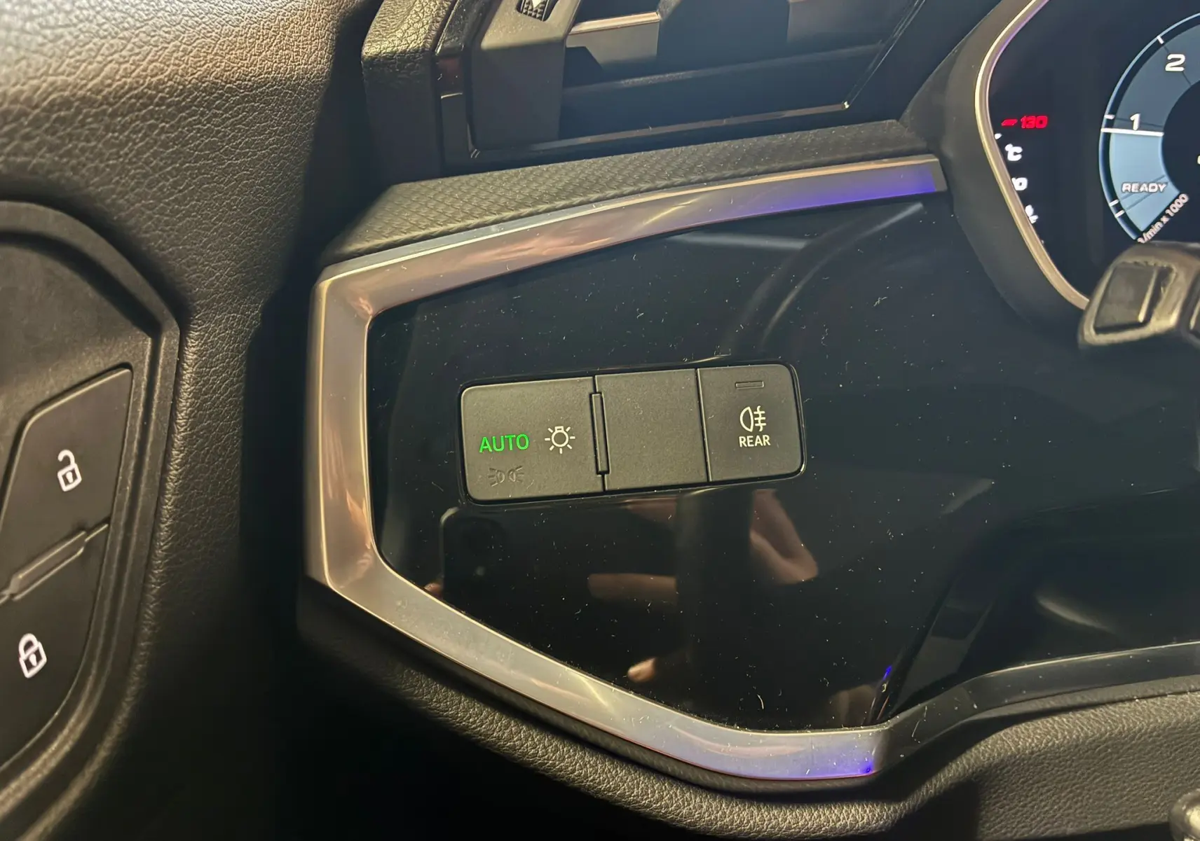 Gros plan sur les commandes d’éclairage à gauche du tableau de bord noir de l’Audi Q3 Sportback gris 2021.