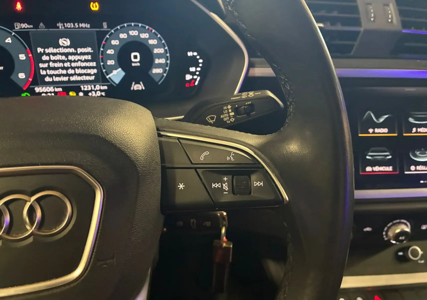 Gros plan sur le volant cuir multifonctions noir et tableau de bord numérique de l'Audi Q3 Sportback gris.