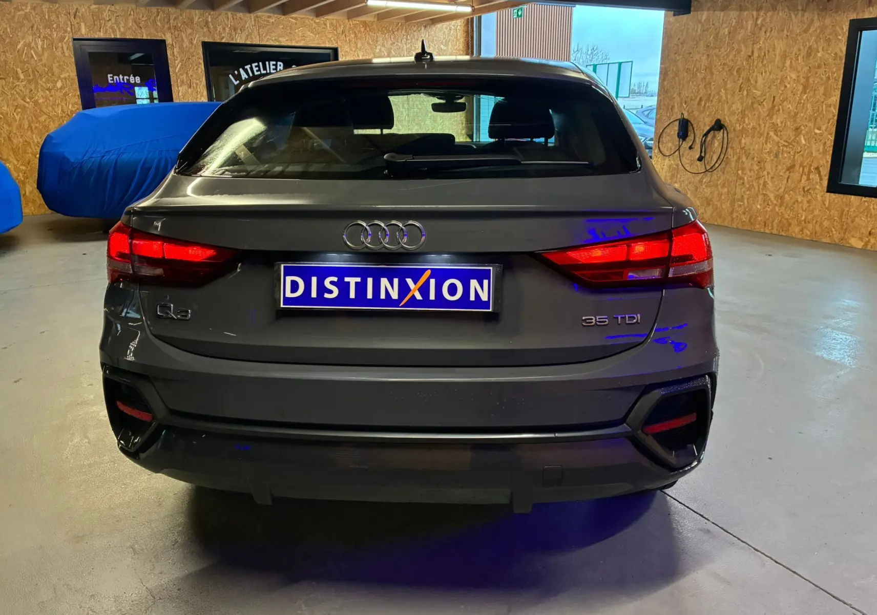 Vue arrière d'un Audi Q3 Sportback gris 35 TDI avec feux LED et logo distinctif dans un garage.