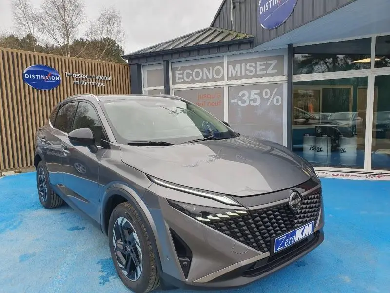Nissan Qashqai Hybrid e-POWER gris Squale métallisé, vue 3/4 avant avec calandre distinctive et jantes alu.