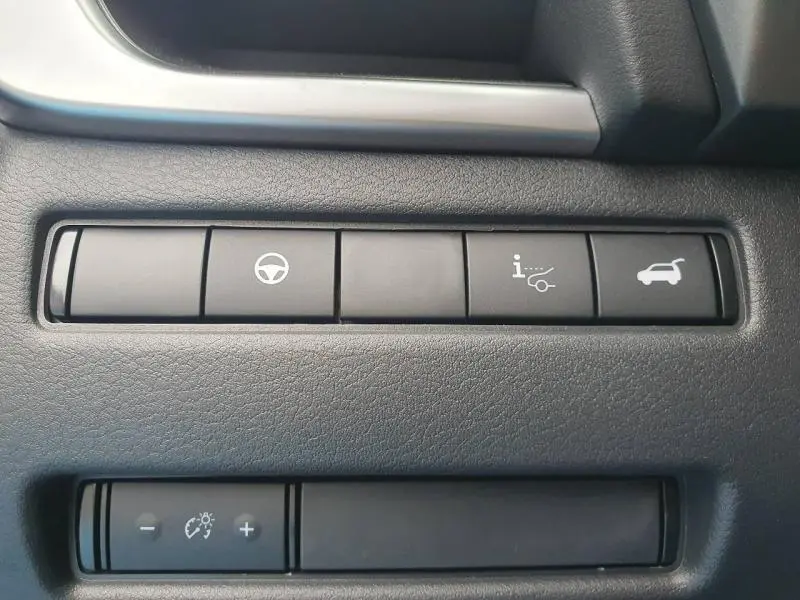 Gros plan sur les boutons de commande noirs du tableau de bord du Nissan Qashqai Hybrid e-POWER gris, avec pictogrammes blancs.